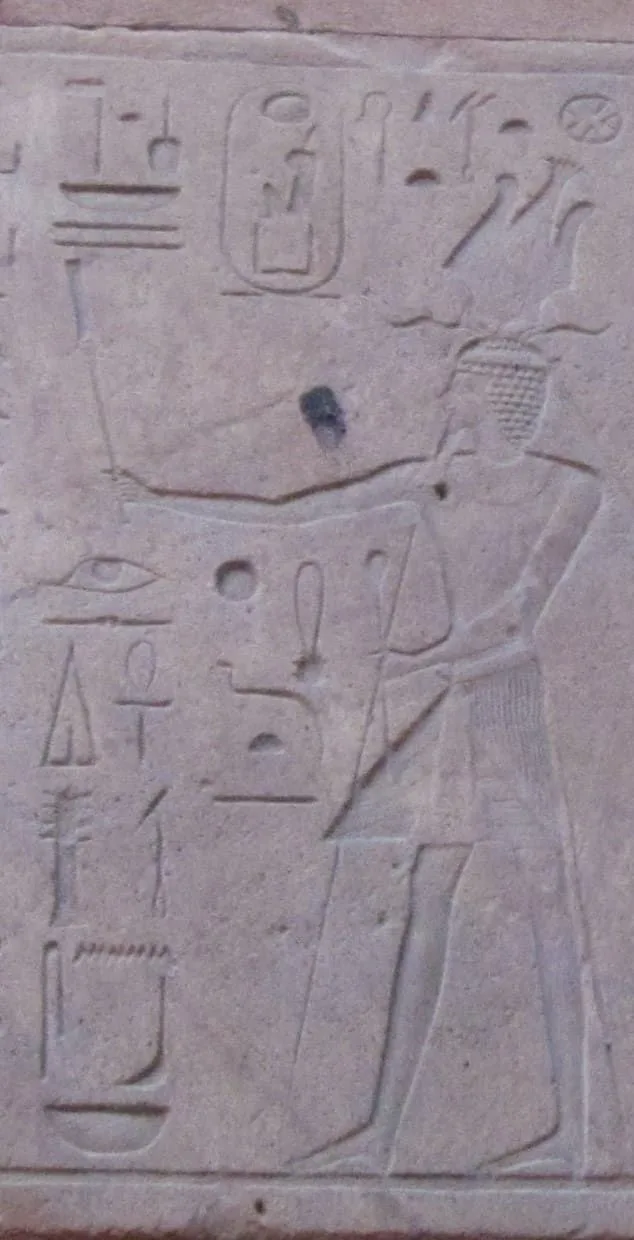Figura 1. Detalle de una de las escenas de la Capilla Roja de Karnak, en la parte superior un cartucho faraónico donde figura el nombre y la titulatura faraónica atribuida a su nombre como faraón «Maatkara/re». Fuente. Licencia: Dominio público