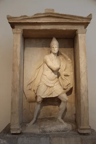 Figura 2. Náiskos o templete de mármol con estatua del soldado Aristonautas. Cerámico de Atenas, s. IV a.C. Fuente. Licencia: Dominio Público